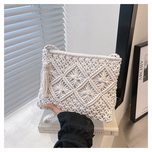 Gros plan sur un sac bandoulière en macramé blanc avec tissage détaillé et longs pompons