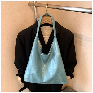 Detail of light blue textured leather tote bag styled with blazer for outfits