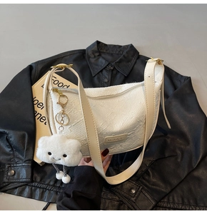 Detail view of white pleated dumpling bag with leather logo and plush cloud charm