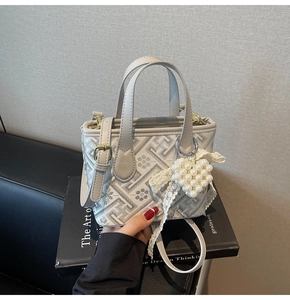 Detail of light gray bucket bag with geometric patterns and pearl heart charm