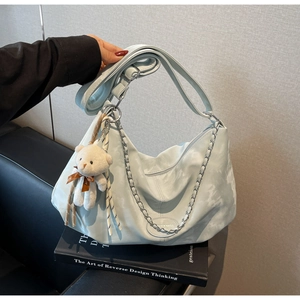 Detail of blue PU hobo bag with silver chain, adjustable strap and cute bear charm