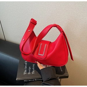 Detail of red lychee grain leather hobo bag with silver buckle and wide shoulder strap
