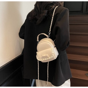 Mini cream backpack with lace trim and bow detail shown on a model's back in a studio setting
