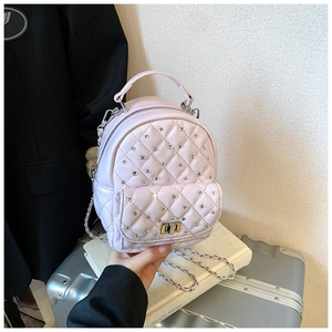 Close-up of pink quilted mini backpack with rhinestone decor and silver chain straps