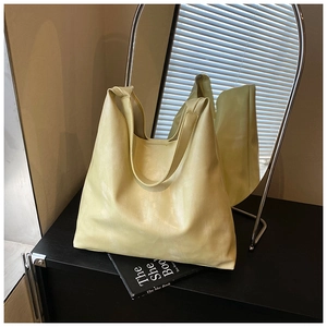 Detail of light yellow faux leather tote bag showing glossy texture and large capacity