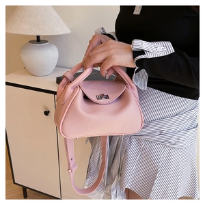 Close-up of pink lychee grain leather handbag with silver rotating lock and shoulder strap