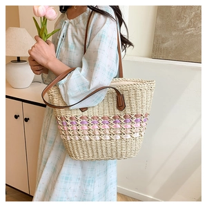 Détail du sac cabas en paille tissée avec bandes colorées et poignées en cuir marron
