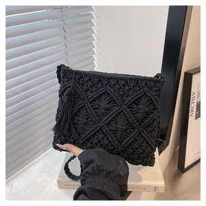 Détail du sac en macramé noir avec pompon et fermeture éclair sur livres décoratifs