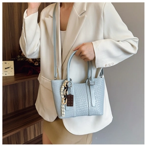 Détail du sac à main bleu clair tissé avec pendentif chocolat et bandoulière en cuir