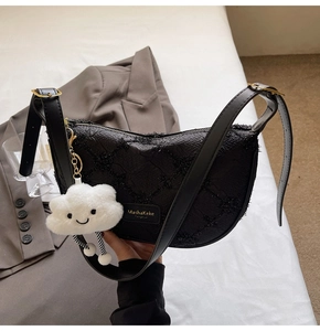 Detail of black fabric dumpling bag with cross-stitch design and cloud charm