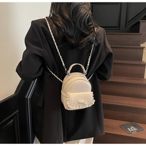 Detailed back view of a mini cream backpack with lace trim and bow on a female model