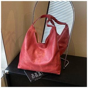 Detail of vintage red tote bag with distressed faux leather texture on a minimal surface