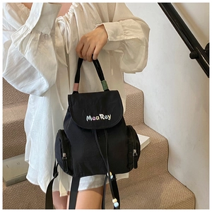 Detail eines schwarzen Stoffrucksacks mit bunter Stickerei und Quasten mit Perlenverzierung