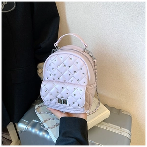 Detail of a mini quilted leather backpack in pink with rhinestones and silver chain