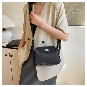 Detail of black pebbled leather texture, silver twist-lock and protective base studs on bag