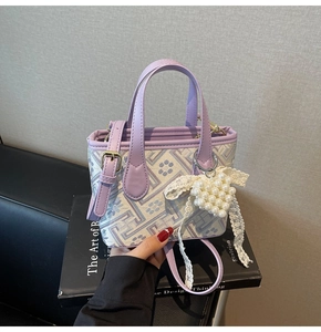 Detailed view of lavender handbag with jacquard pattern and pearl heart charm accessory