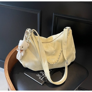 Detail of cream PU leather hobo bag with silver chain and cute white bear charm