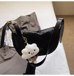 Detail of black jacquard half-moon bag with adjustable leather strap and plush charm