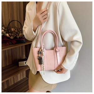 Détail du sac à main rose tissé avec chaîne en acrylique et breloque chocolat