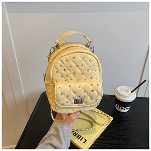 Detailed shot of yellow quilted mini backpack with rhinestone studs and chain strap