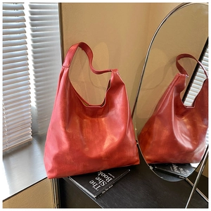 Detail of red matte leather tote bag with natural texture and seamless wide shoulder strap