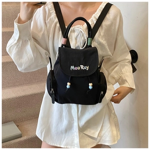 Nahaufnahme des schwarzen Nylon-Rucksacks mit bunten MeaRey-Stickereien und Perlenzug