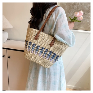 Détail du sac cabas en paille avec maille bleue ajourée et anses en cuir marron