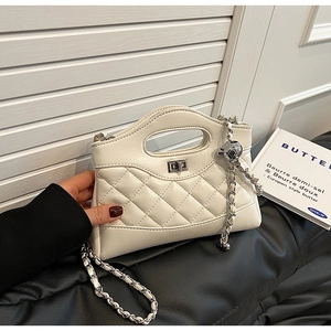 Detail of white quilted crossbody bag with silver chain strap and metal ball adjuster