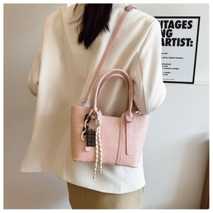Détail du sac cabas rose tressé avec chaîne en résine et charms décoratifs