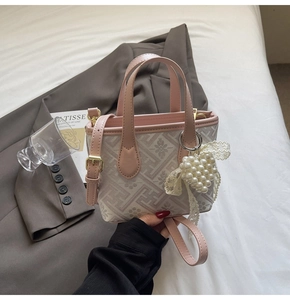 Detail of canvas bucket bag with floral patterns, leather straps and pearl heart charm