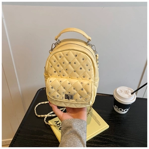 Detail of light yellow quilted backpack with rhinestones and metal chain strap