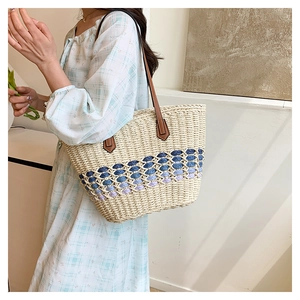 Détail du sac cabas en paille tissée avec dentelle dégradée bleue et anses en cuir