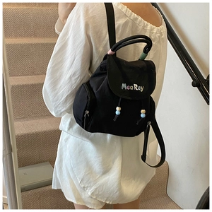 Detail eines schwarzen Mini-Rucksacks aus Nylon mit bunten MeaRey-Stickereien und Perlenzug