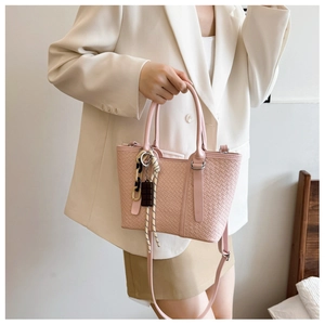 Détail du sac bandoulière rose tressé avec chaîne acrylique et pendentif texturé