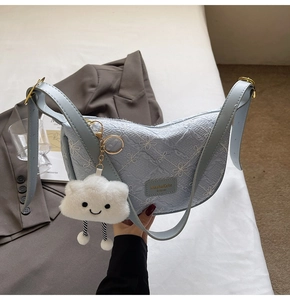 Detail of light blue crescent bag with floral embroidery and white cloud plush charm