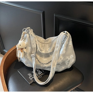 Detail of silver metallic puffy cloud tote bag with chain strap and teddy bear charm