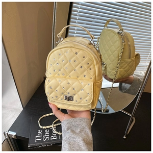 Close-up of a yellow quilted mini backpack with rhinestones and metal chain straps