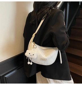 Detail of white textured crescent bag with MashaKeke plaque and cute cloud plush charm