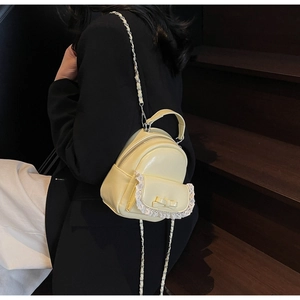 Detail of yellow mini backpack with lace pockets and bow on a model against stairs