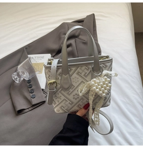 Detail of jacquard bucket bag with pearl heart charm and lace bow on grey blazer