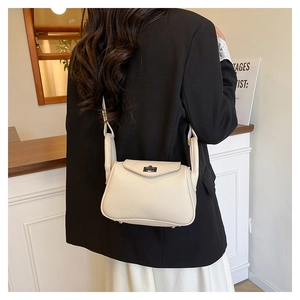 Rear view of a model wearing the cream pebbled leather mini crossbody bag with metal lock