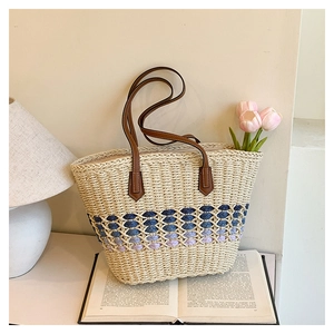 Détail d'un sac cabas en paille avec motif de vagues bleues et fine bandoulière en cuir