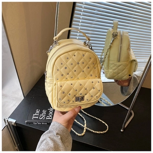 Close-up of yellow quilted mini backpack with rhinestone details and gold chain strap