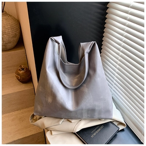 Detail of silver tote bag with metallic texture on light grey blazer in natural light
