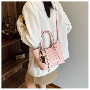 Sac à bandoulière rose à texture tissée avec breloque chocolat porté par un mannequin