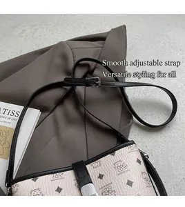 Detail of white textured bucket bag featuring cartoon cat patterns and black shoulder strap