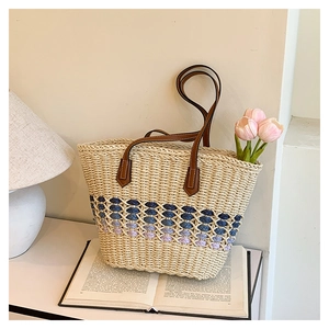 Détail du sac cabas en paille tissée avec motif dégradé et anse en cuir, décor chaleureux