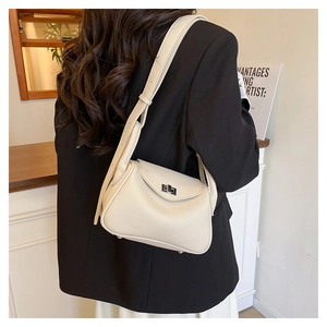 Detail of cream pebbled leather shoulder bag showing the silver rotary buckle and texture