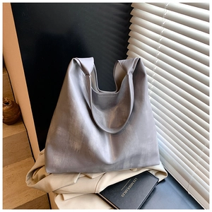 Detail of grey-blue leather tote with soft handle knotting against shutter shadows