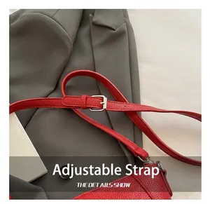 Détail de la bandoulière en cuir rouge avec boucle de réglage en métal argenté brillant